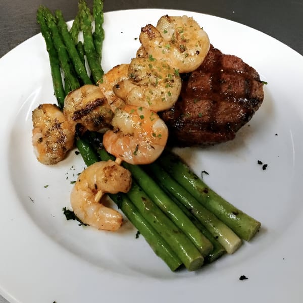 Grilled steak and shrimp with asparagus spears on a white plate at Jimmy Joy's Log Cabin Inn.