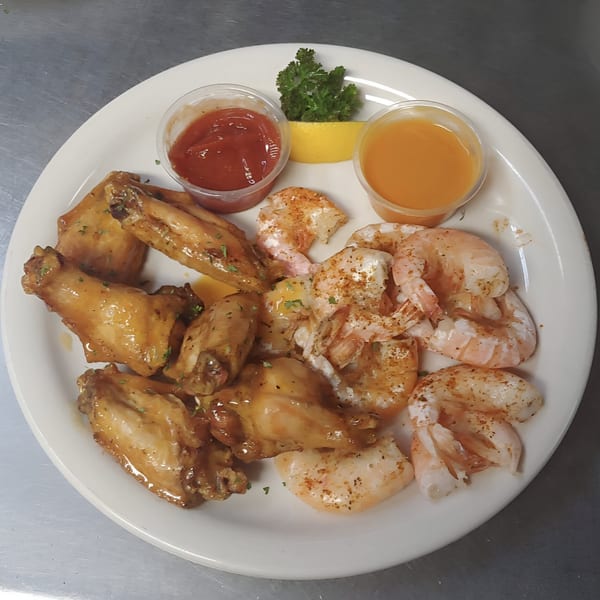 A plate of golden-brown chicken wings and seasoned shrimp with two dipping sauces and a lemon wedge.