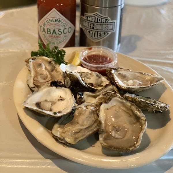 A plate of fresh oysters with lemon, cocktail sauce, Tabasco, and a Harley-Davidson mug.